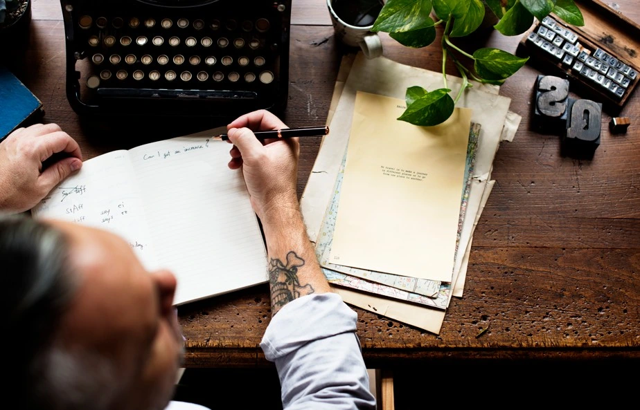 Man writing notes beside vintage typewriter