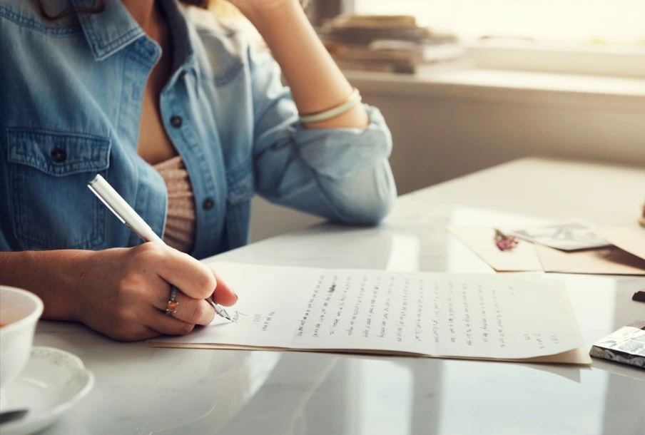 Woman writing a letter on paper at a bright desk