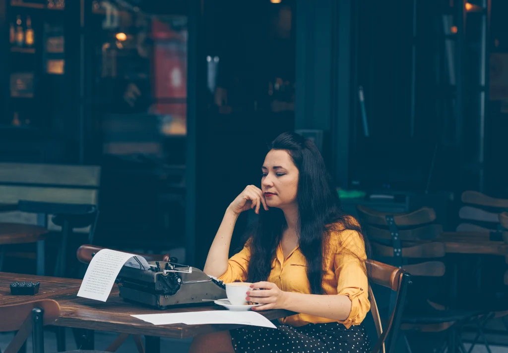 woman-yellow-top-long-skirt-sitting-drinking-coffee-cafe-terrace-looking-thoughtful-daytime